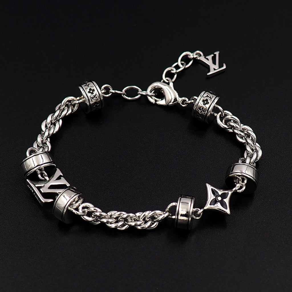 Louis Vuitton charm bracelet closeup, silver linked chain with logo blocks and star charms