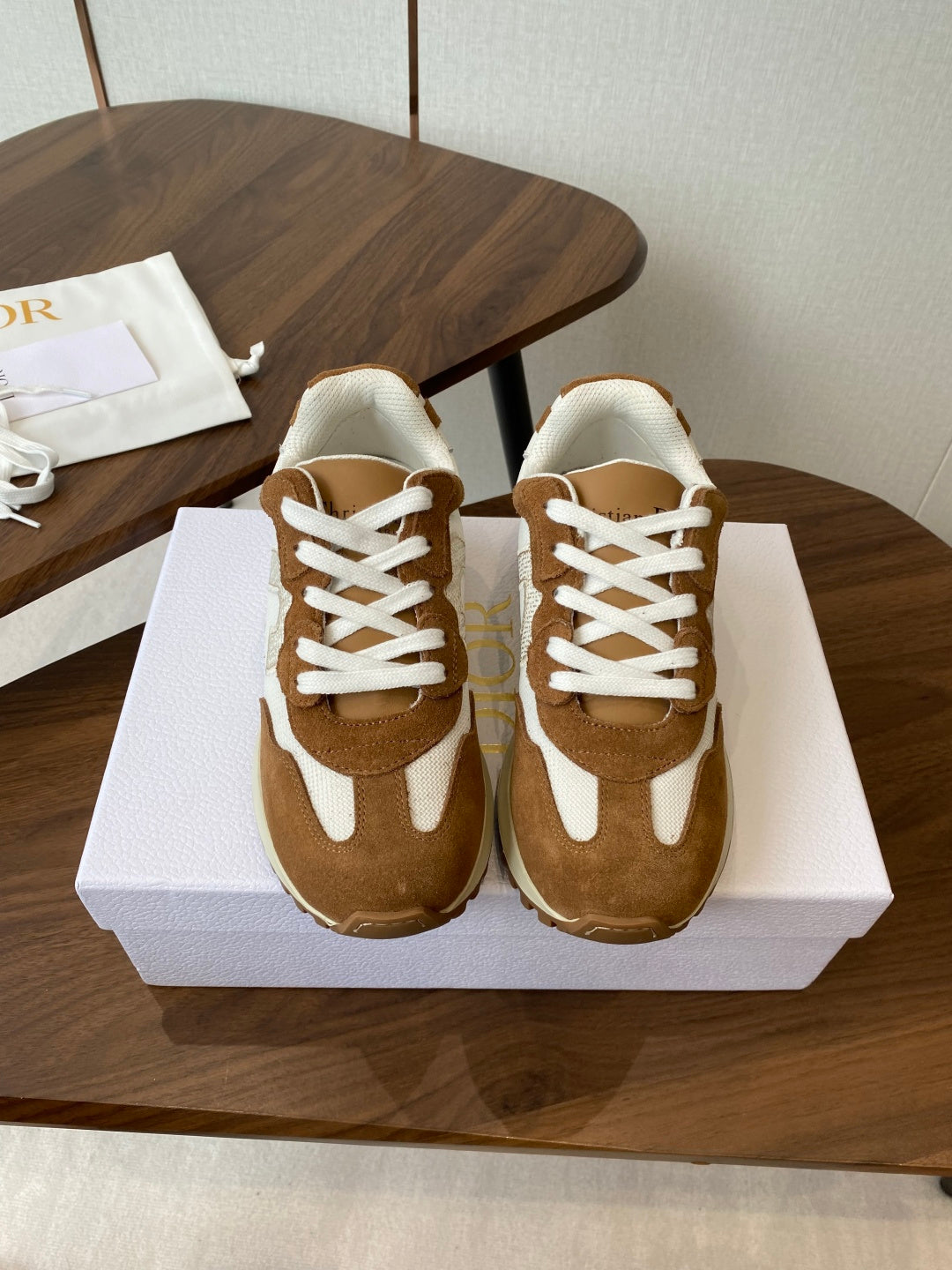 Brown and white sneakers with white laces, pair on white shoebox