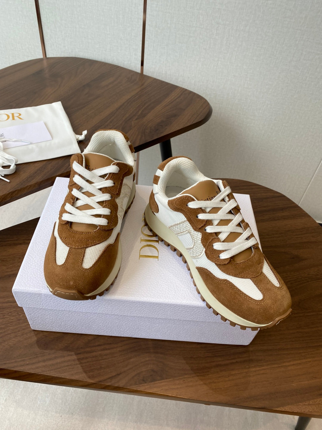 Brown and white lace-up sneakers on white shoebox, three-quarter view