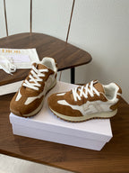 Brown and white Dior sneakers with white laces on white shoebox, angled view