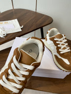 Brown and white sneaker upper with white laces, collar open on white shoebox