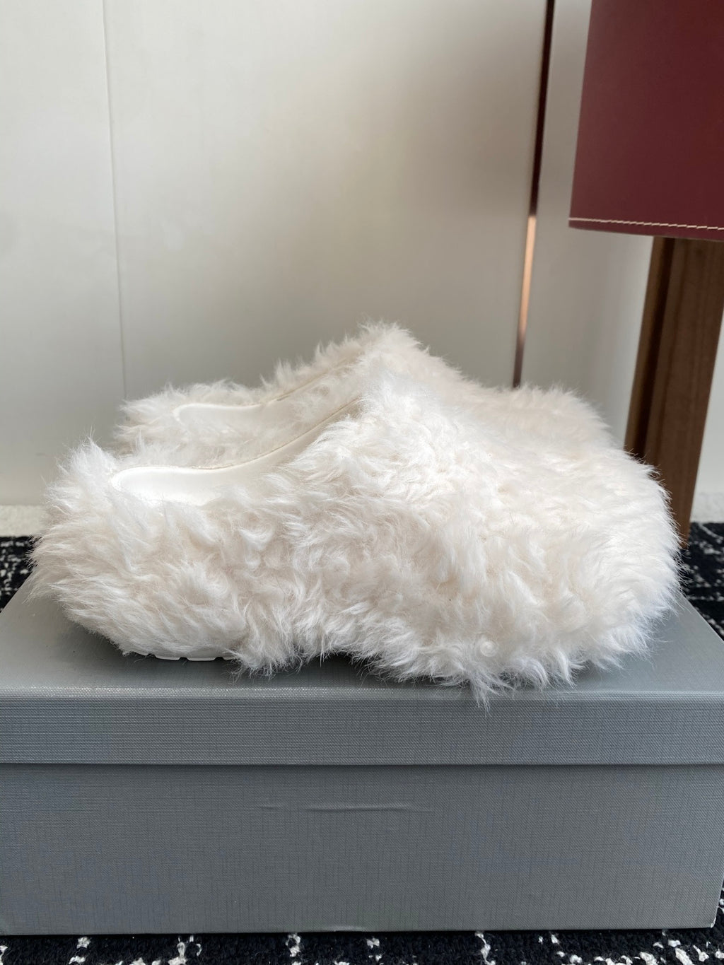 White faux-fur slide sandals on a light-gray box, open toe and low profile