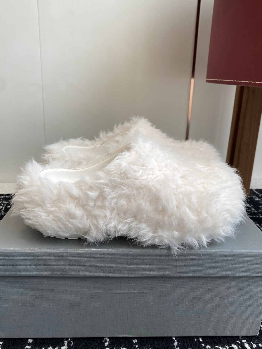 White faux-fur slide sandals on a light-gray box, open toe and low profile