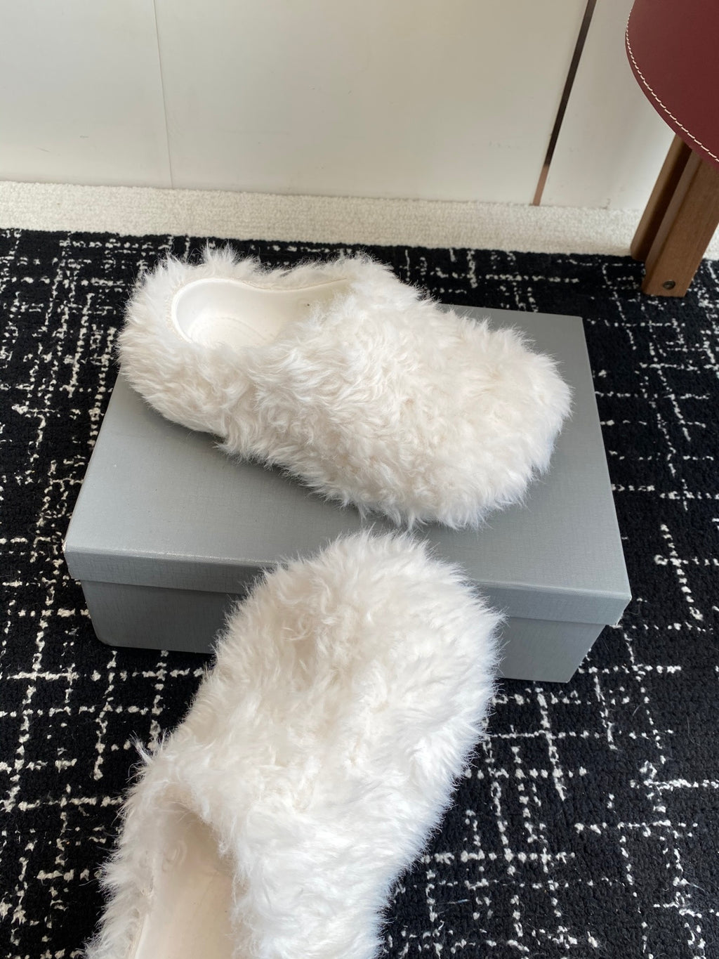 White faux-fur slide sandals with open toe and wide cuff, placed on box