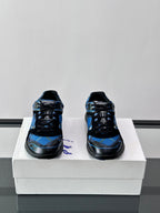 Pair of blue and black sneakers shown from the front on a white shoebox