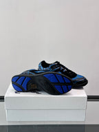 Blue and black sneakers with patterned outsole visible in a rear three-quarter view
