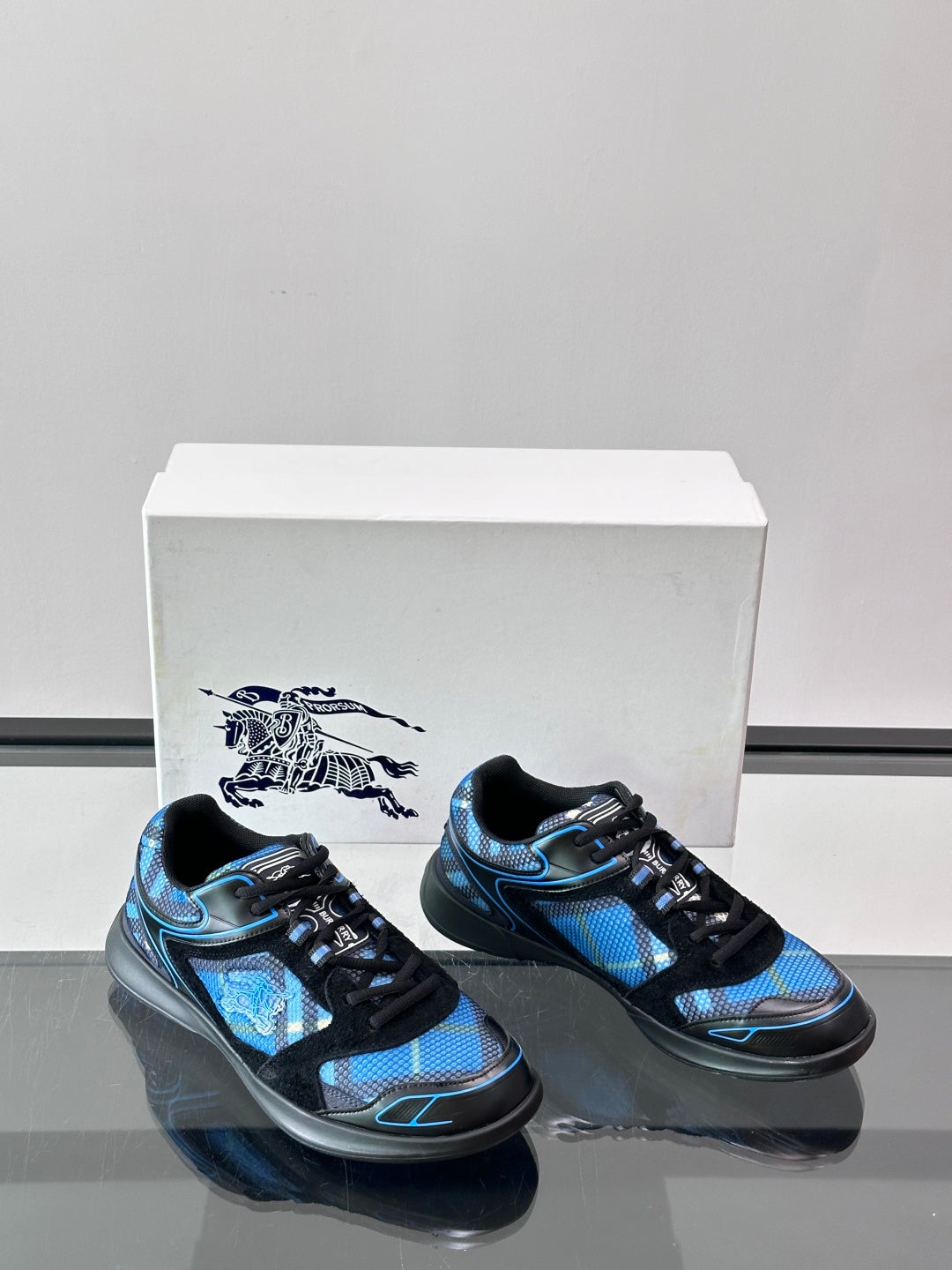 Two blue and black sneakers with lace-up uppers and low-profile black soles