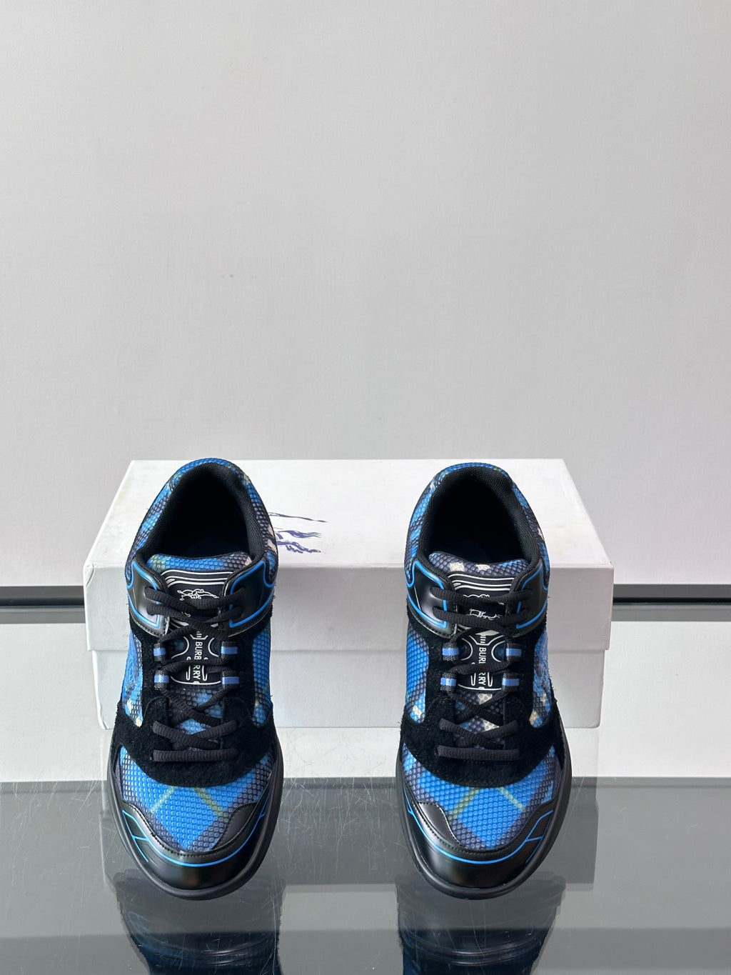 Blue and black sneakers shown from the back on a white shoebox