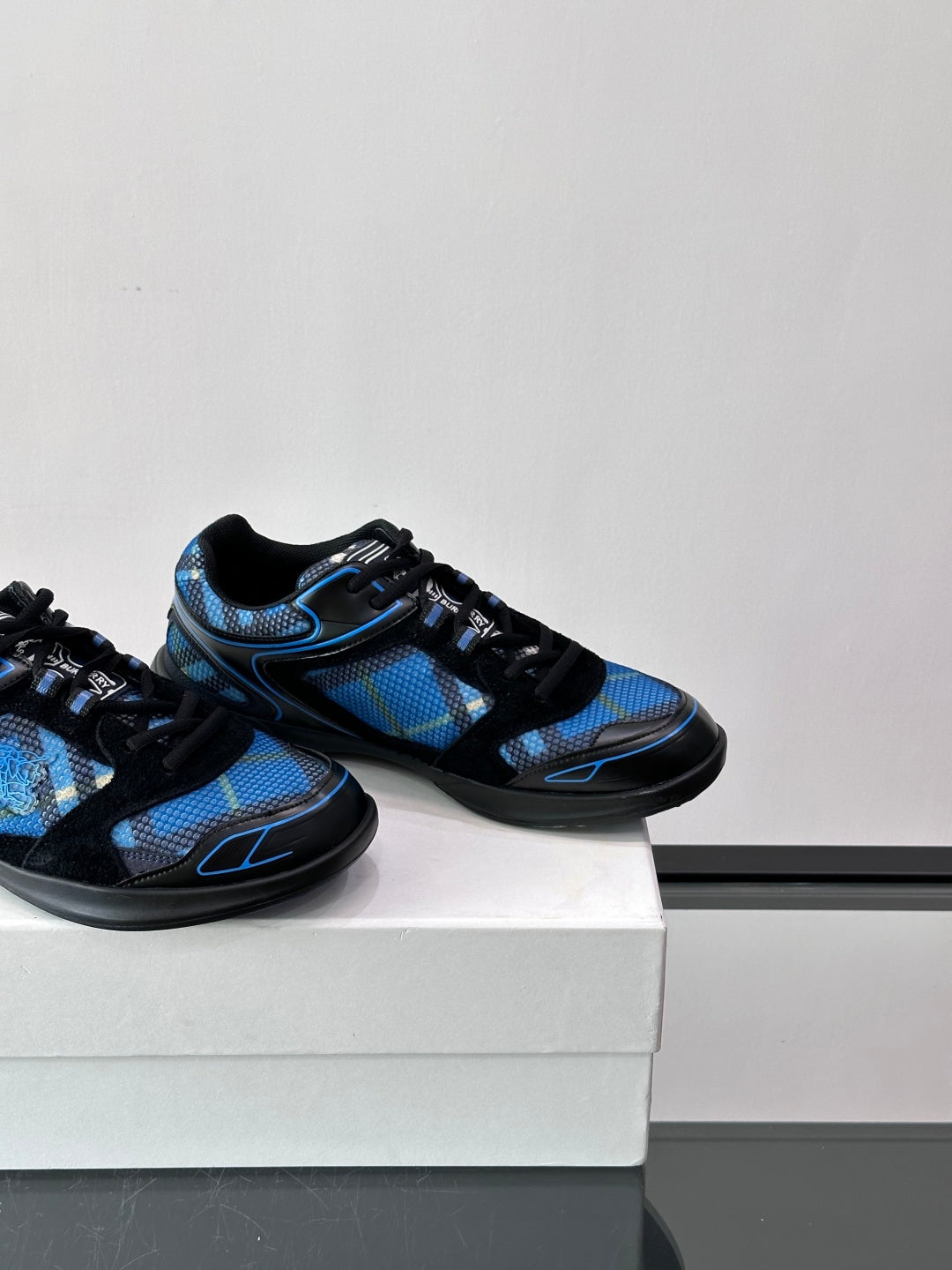 Two blue and black sneakers placed side by side on a white shoebox