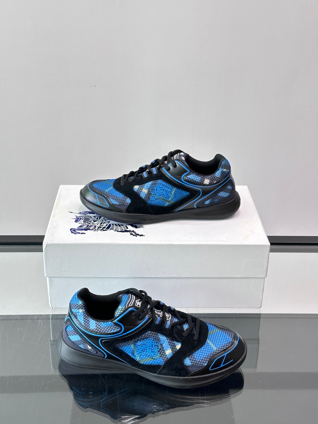 Blue and black sneakers on a shoebox, side view with sculpted sole