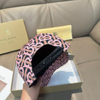 Burberry cap with pink and black monogram pattern and black strap across the brim