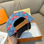 Louis Vuitton cap side view: blue denim with red mushrooms, tan leather strap across brim.