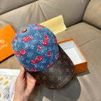 Louis Vuitton cap on hand: blue denim crown with red mushrooms, dark monogram brim.