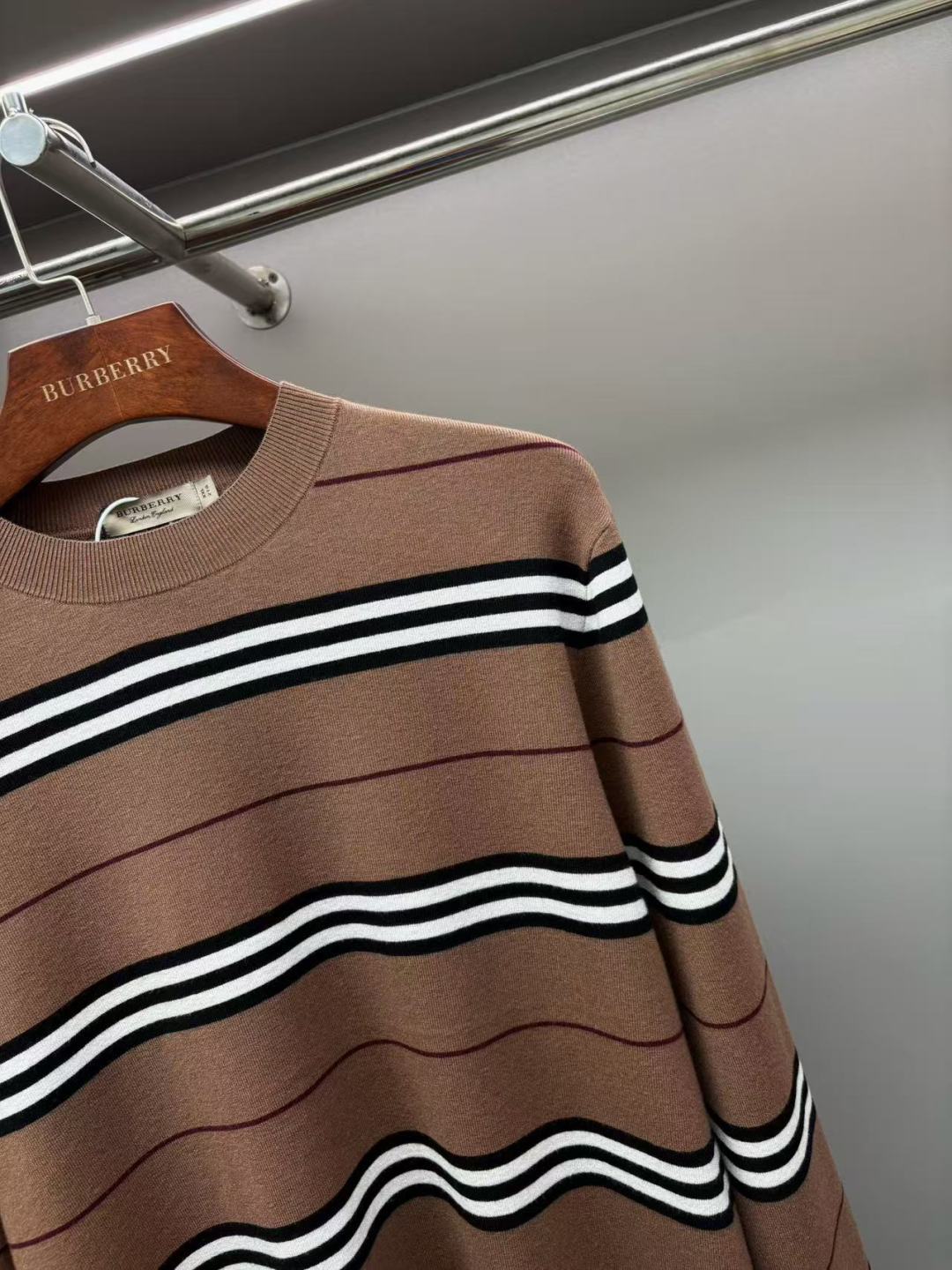 Close-up of brown crew-neck knit sweater with black-and-white stripe bands