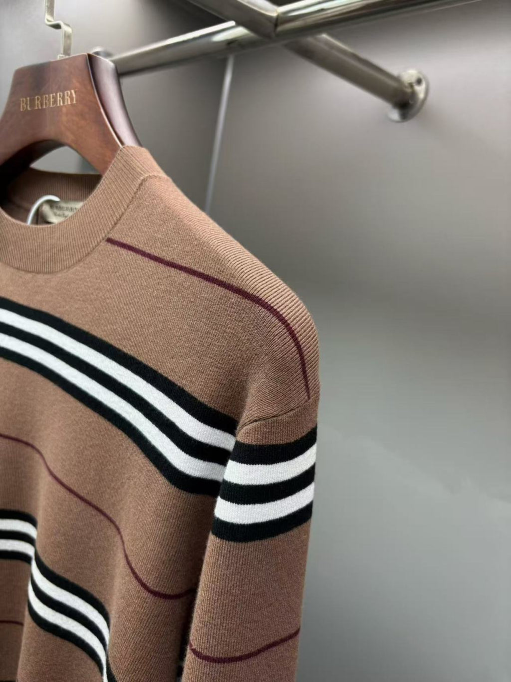 Brown knit sweater with black-and-white striped sleeve band and crew neck