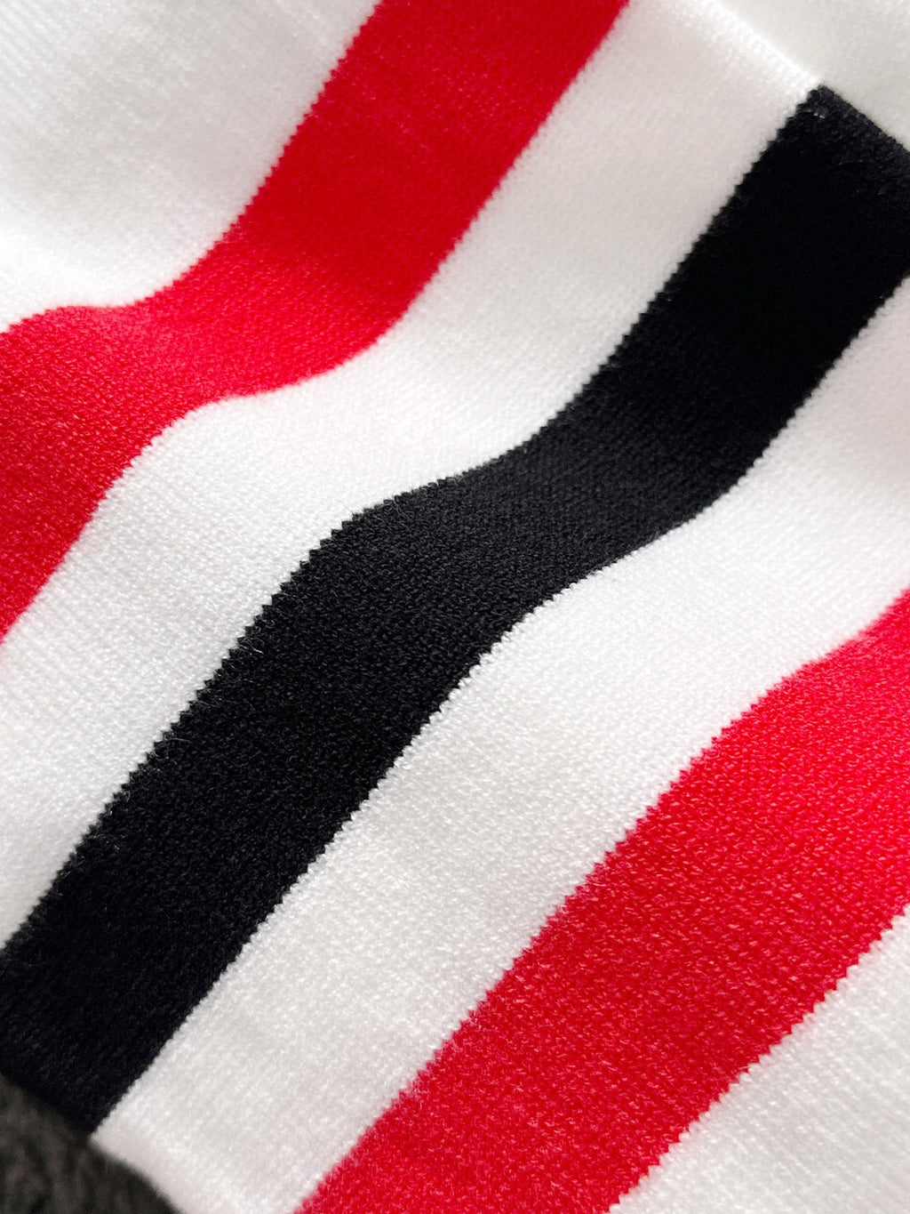 Close-up of red, black, and white striped fabric band on a white sleeve