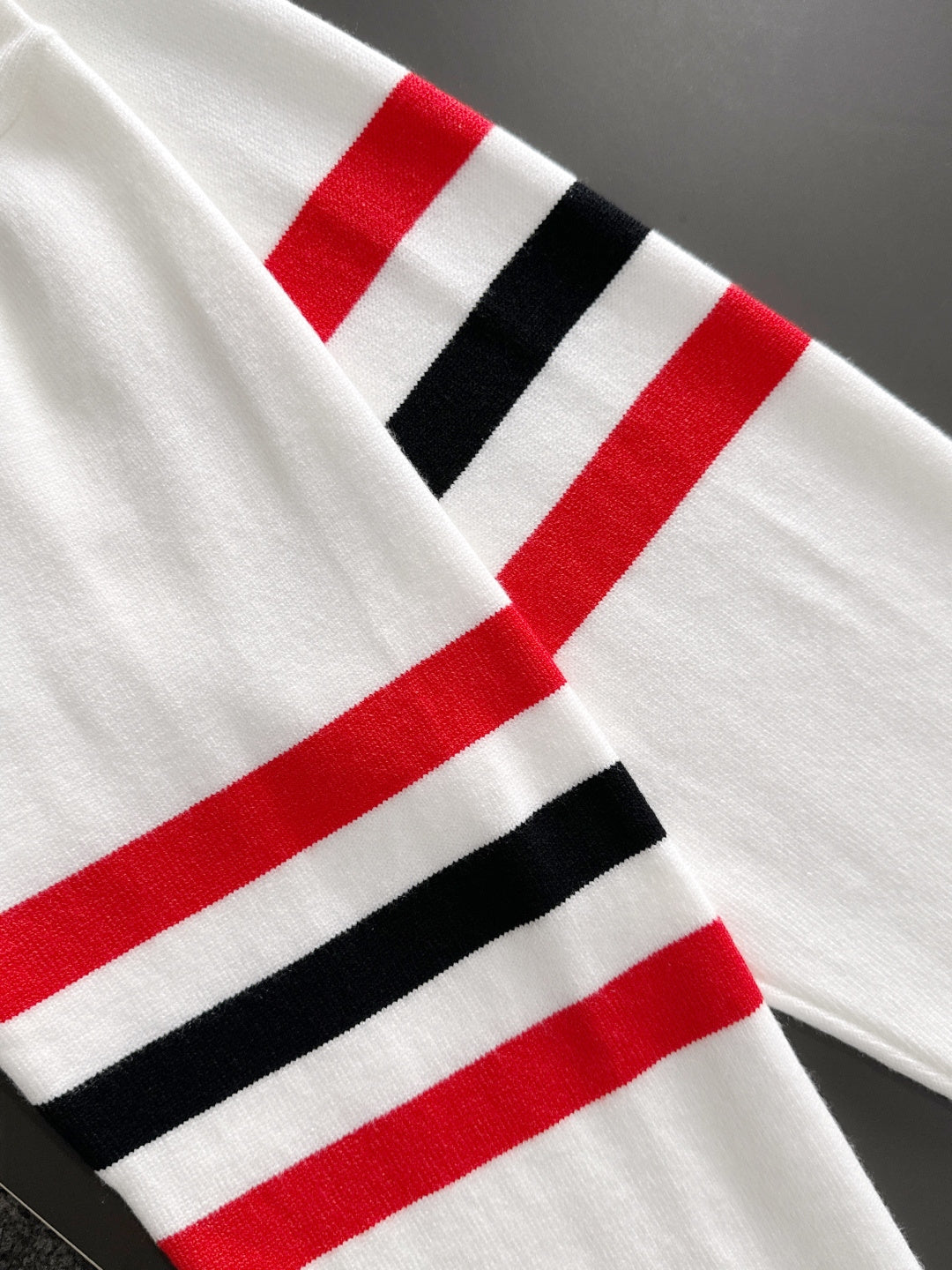 White sweatshirt sleeve with red, black, and white stripe band