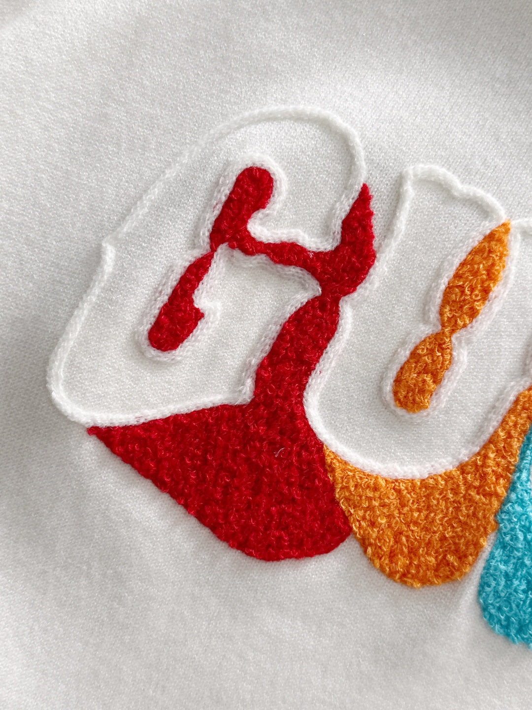 Close-up of embroidered Gucci lettering on white fabric