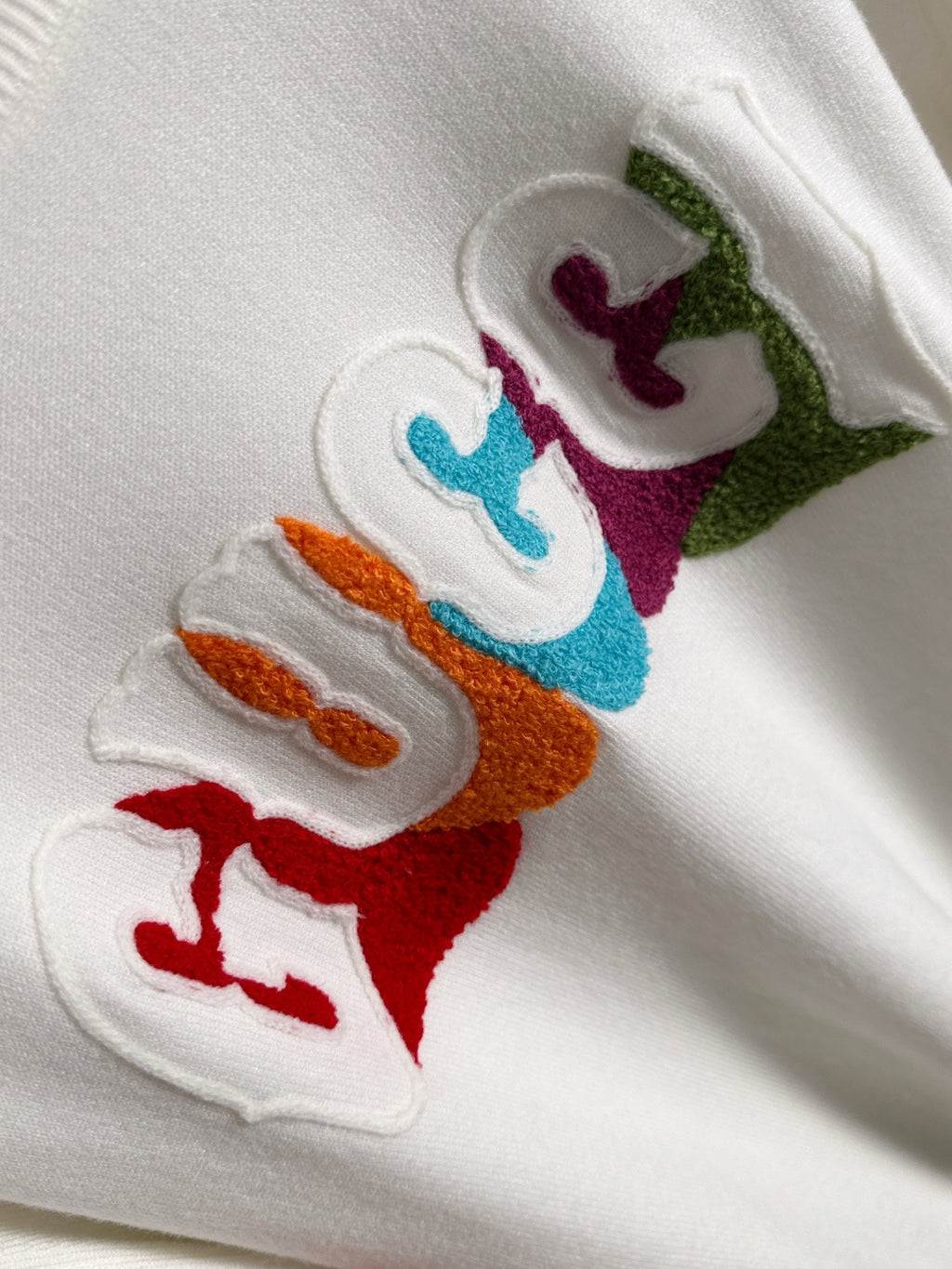 Close-up of multicolor Gucci logo embroidery on white fabric