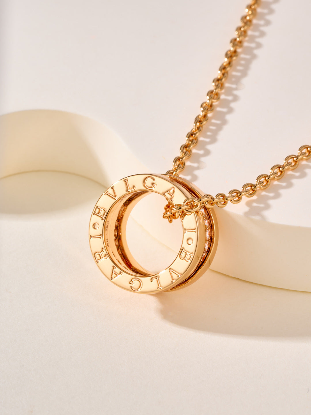 Gold-tone circular pendant with engraved Roman numerals on a chain necklace