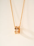 Gold-tone chain necklace with stacked ring pendant and small gemstone accents