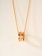 Gold-tone chain necklace with stacked ring pendant and small gemstone accents