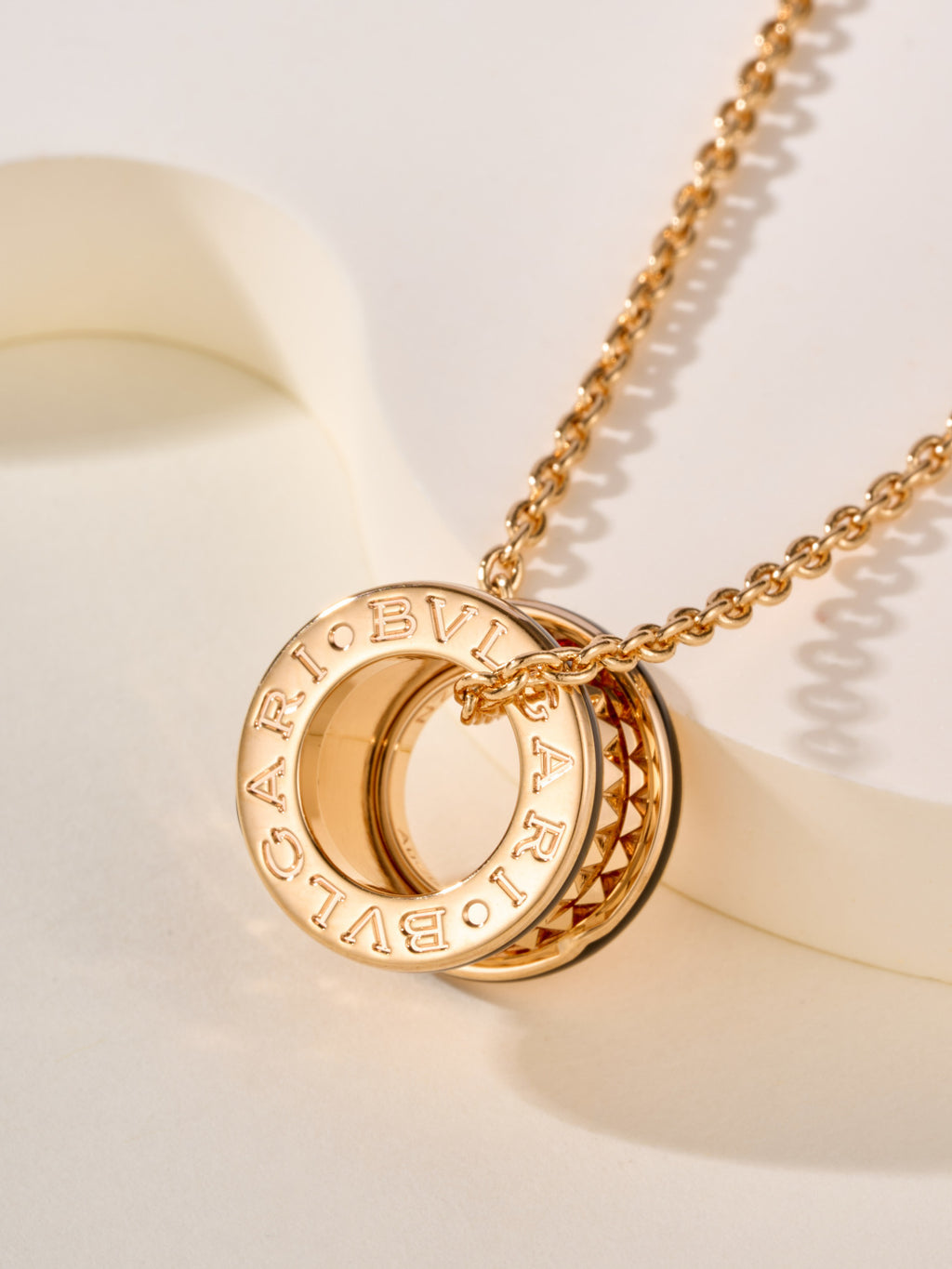 Bvlgari circular logo pendant with engraved lettering on a gold-tone chain