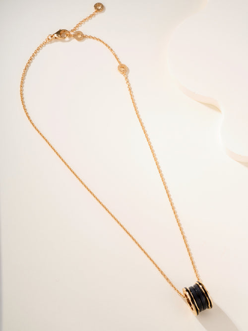 Gold-tone necklace with long chain and black enamel round pendant at end