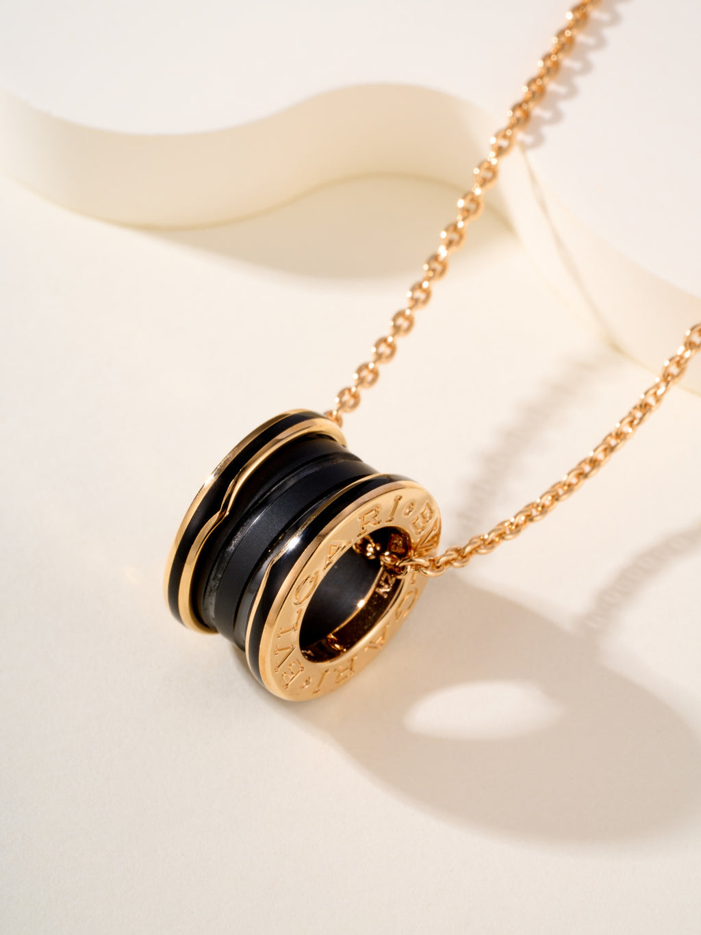 Gold-tone necklace with round black-and-gold pendant featuring engraved Bvlgari detail