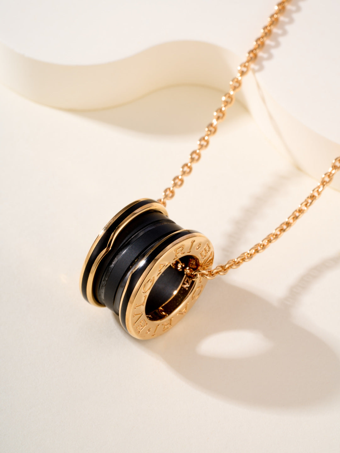 Gold-tone necklace with round black-and-gold pendant featuring engraved Bvlgari detail
