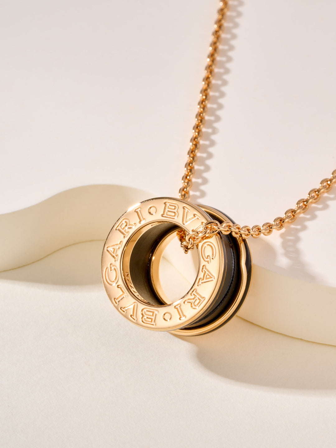 Gold-tone necklace with large circular Bvlgari logo pendant and black enamel inset