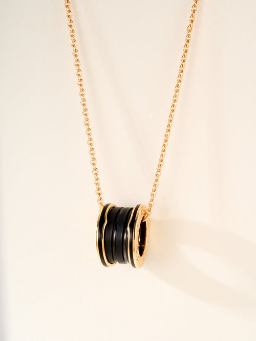 Gold-tone necklace with round pendant featuring black enamel rings