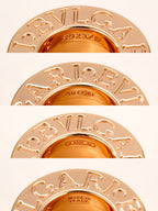 Gold-tone ring pendant close-up with engraved letters around the bezel
