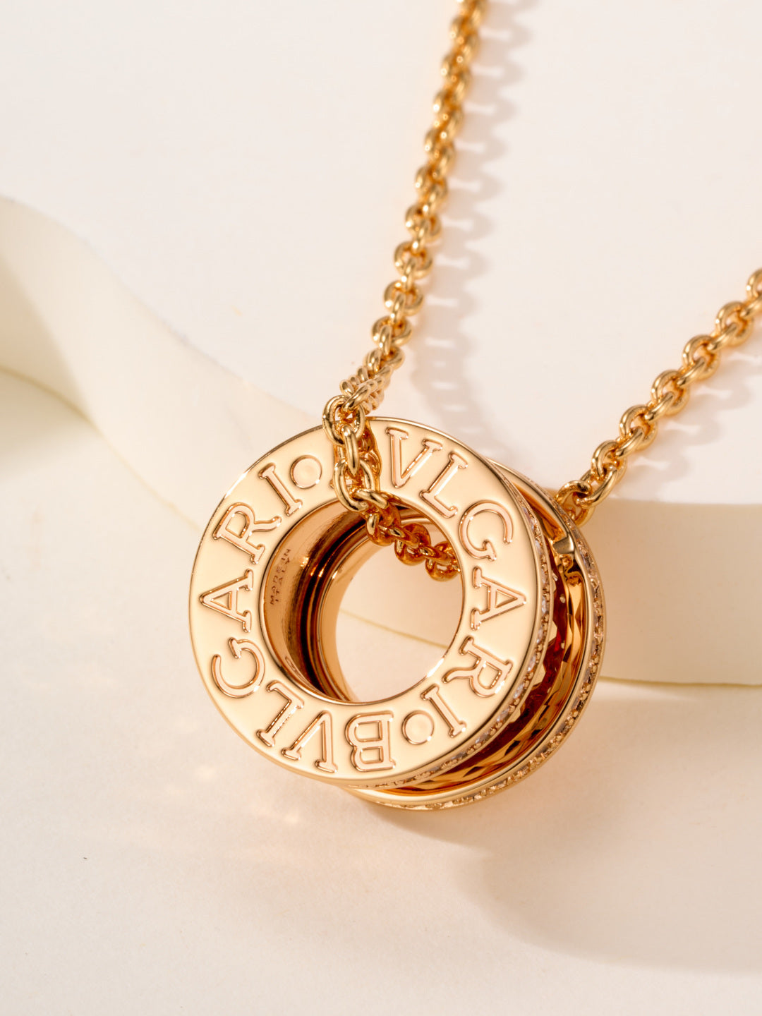 Gold-tone necklace with circular monogram pendant and engraved letter details