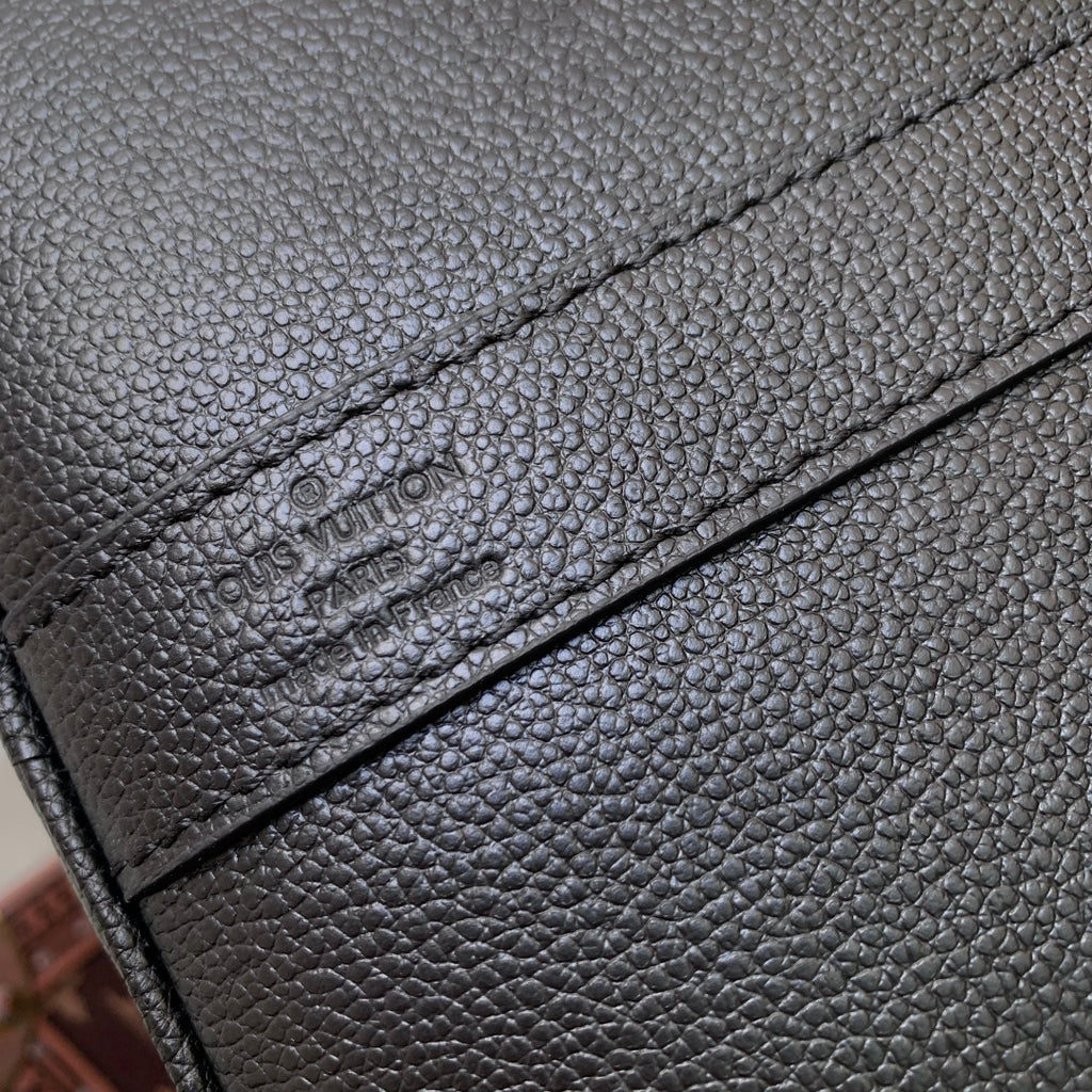 Louis Vuitton men’s dark blue leather bag close-up of embossed logo on leather