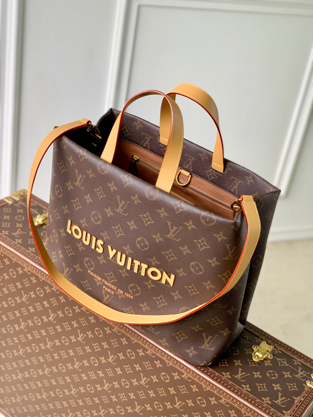 Louis Vuitton monogram tote bag with tan handles and visible zipper top
