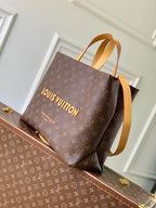 Louis Vuitton monogram tote bag with tan trim, top handles, and structured base