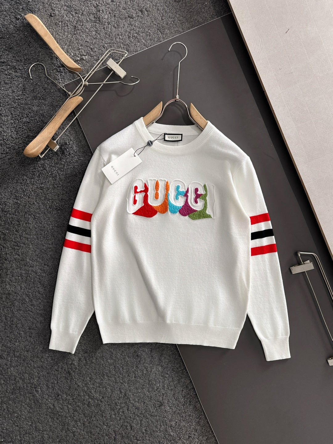 White crewneck sweatshirt with multicolor Gucci logo and red/black/white striped sleeves