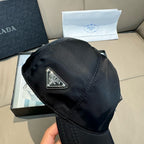 Black baseball cap with triangular Prada logo emblem on the front panel.