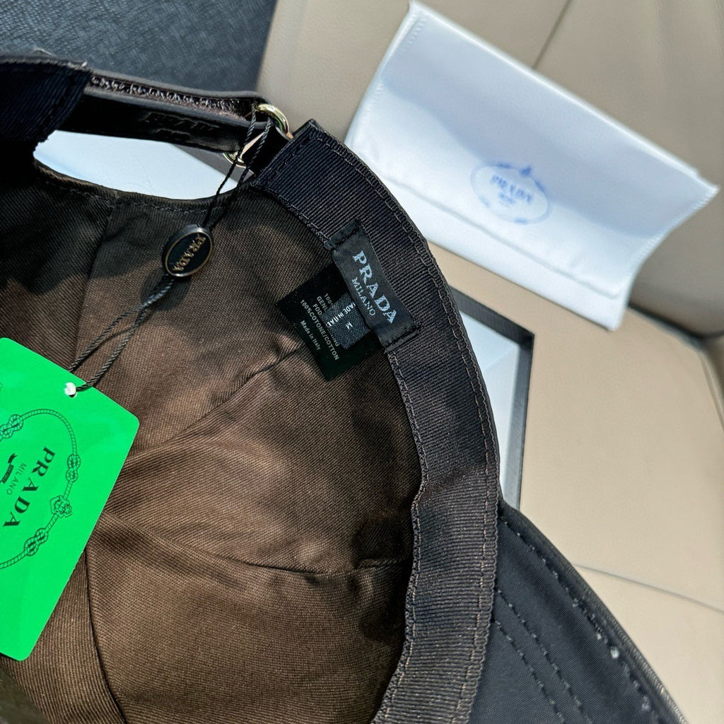Black cap with fabric lining and adjustable strap; Prada logo label.
