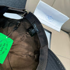 Black cap with fabric lining and adjustable strap; Prada logo label.