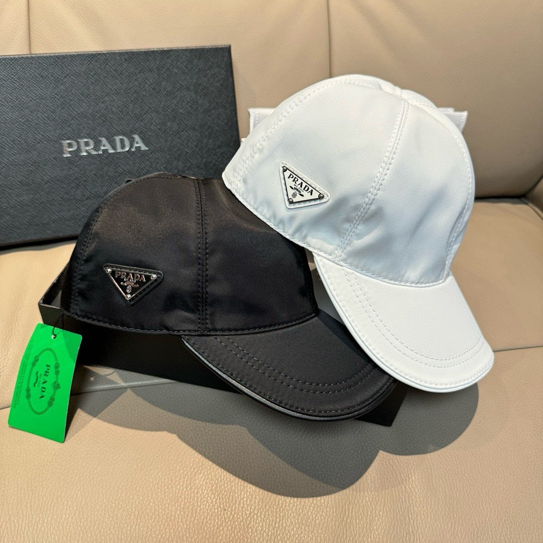 Black and white Prada caps with triangular logo patches and curved brims.
