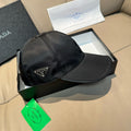 Black fabric baseball cap with triangular Prada logo patch and curved brim.