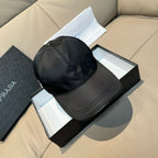 Black baseball cap with curved brim and stitched panels; triangular Prada logo patch.