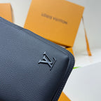 Louis Vuitton bag in dark blue grained leather, close-up of LV embossed metal emblem.
