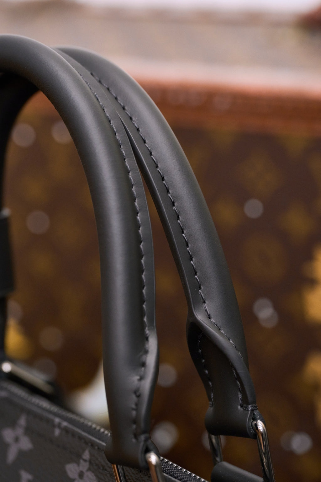 Black leather top handles with contrast stitching on monogram handbag