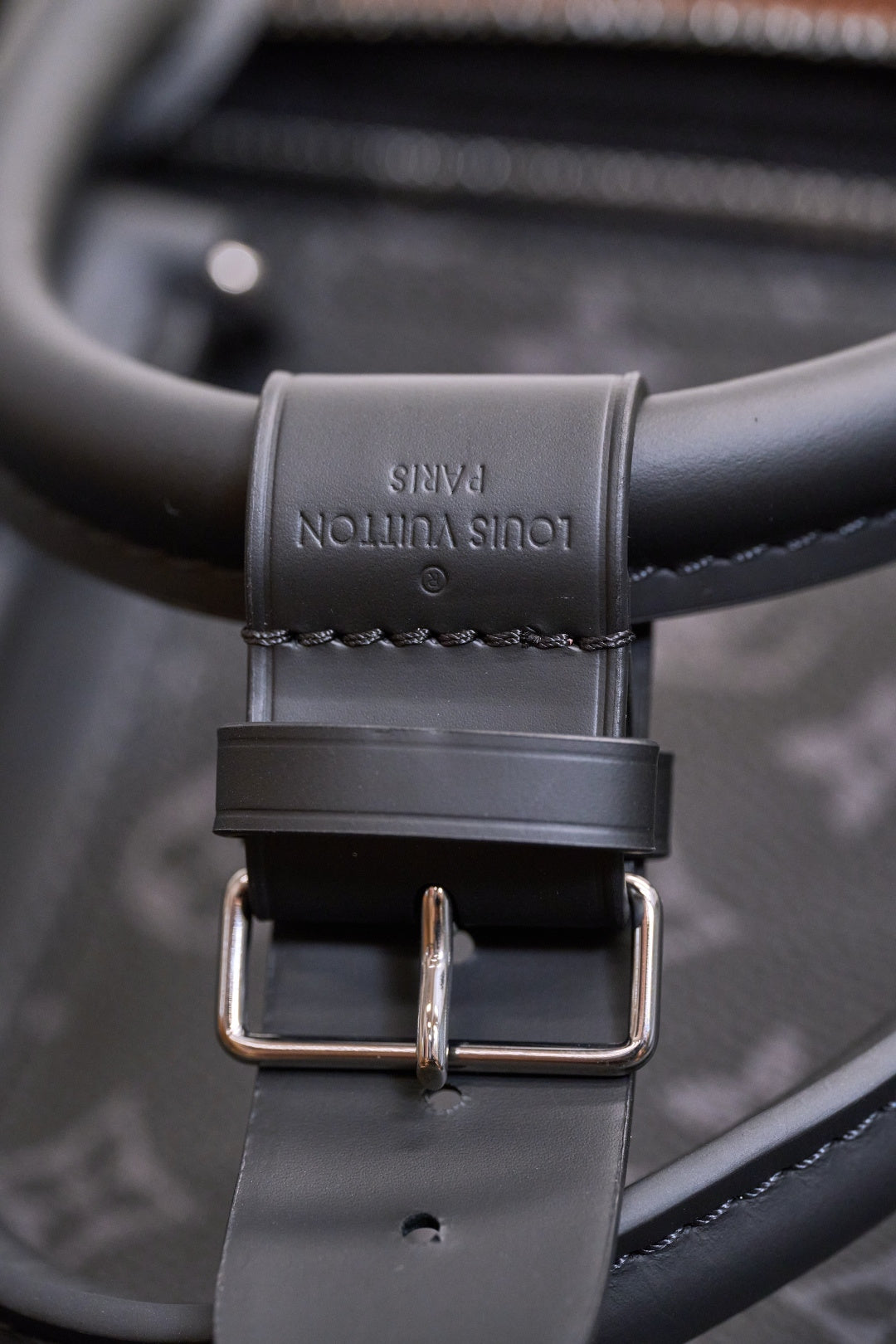 Adjustable leather shoulder strap with buckle and stitched monogram trim