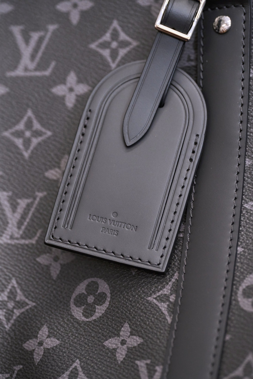 Front luggage-tag style pocket with logo on dark monogram handbag
