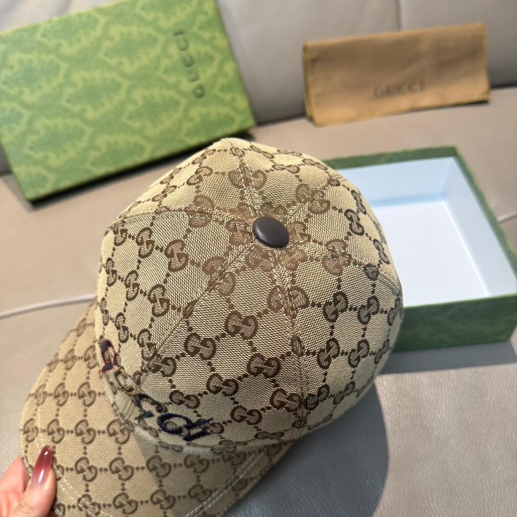 Tan GG monogram baseball cap with small black top button and curved brim.