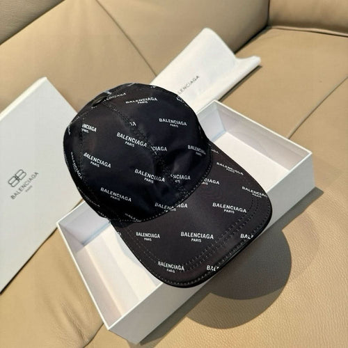 Balenciaga cap in black with repeating BALENCIAGA logo pattern, inside a box.